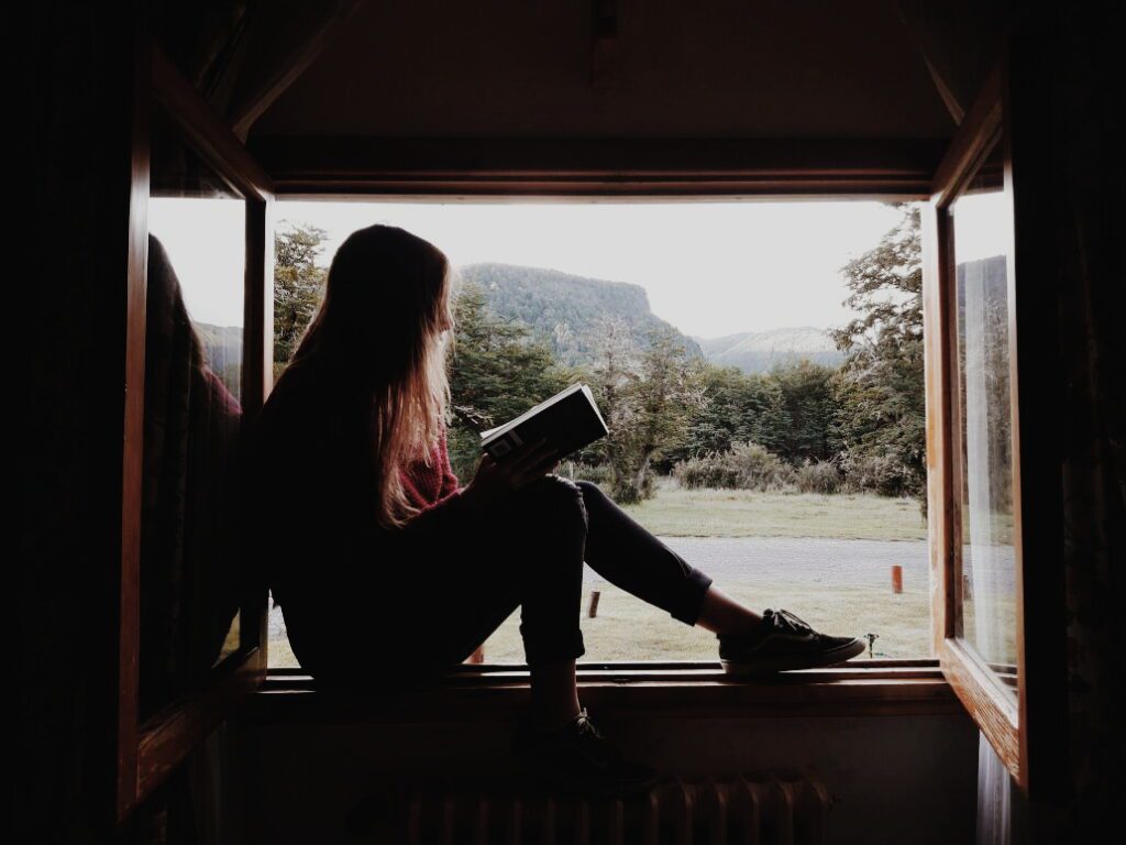 Girl reading buddhist books for conscious travelers at the mountain 