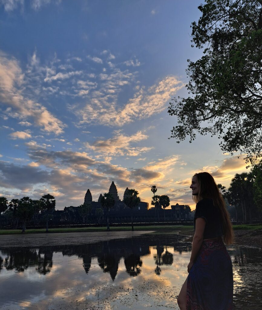 View of Angkor Wat temple complex at sunrise with reflection in water